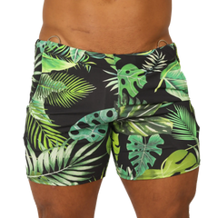 Black swim trunks with vibrant green and lime tropical leaf pattern and metallic silver waistband rings by Gigo Forest