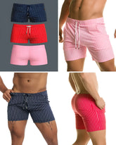Three pairs of short, vertically striped swim trunks in navy, red, and pink with white drawstring waistbands.