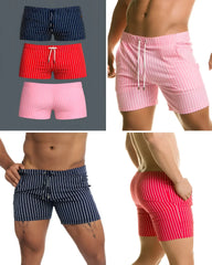 Three pairs of short, vertically striped swim trunks in navy, red, and pink with white drawstring waistbands.