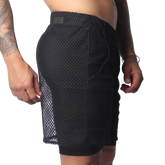 Black athletic shorts in a large-grid fishnet material with a solid inner layer and a branded elastic waistband.