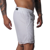 White athletic shorts made of a sheer, open-mesh material with an elastic waistband and small black logo patch.