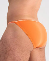 Bright orange glide micro brief featuring soft fabric and a matching elastic waistband with brand logo repeat