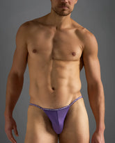 Purple glide micro brief men’s thong with elastic waistband featuring repeated teamsteam white lettering design