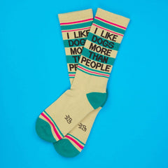 Cream-colored crew socks with teal and pink stripes featuring i like dogs more than people text in black lettering