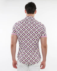 A man wearing a grid parquet printed performance short sleeve shirt with pink purple and cream geometric pattern