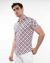 A man wearing a short-sleeved grid parquet printed performance shirt with pink navy blue and cream geometric pattern
