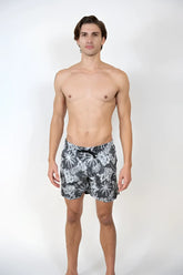 Men’s dark gray Hawaiian print swim shorts with white tropical leaf pattern and black drawstring waistband