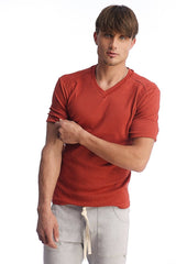 A man wearing a rust-colored hybrid v-neck shirt with ribbed cuffs and hem in cinnabar color