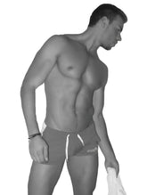 A man wearing icker sea air fitness side stripe blue shorts with white drawstrings and logo on the lower right leg