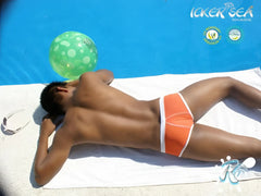 Orange swim trunks with white trim from icker sea cheeky mini bikini swimwear lying on towel beside pool