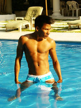 A man wearing icker sea cord contrast trim and stitching bikini swimwear in blue and white standing in a pool