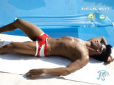 A man lies by the pool wearing icker sea eyelets square cut trunk swimwear in red with silver buttons