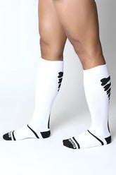 White kennel club bones knee high athletic socks with black wing patterns and heel branding shown from back side