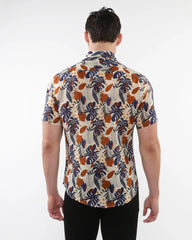 A man wearing a lightweight linen tencel short-sleeved shirt with a navy blue orange and cream tropical pattern on beige