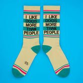 Cream-colored crew socks with teal and pink stripes featuring i like dogs more than people text in black lettering