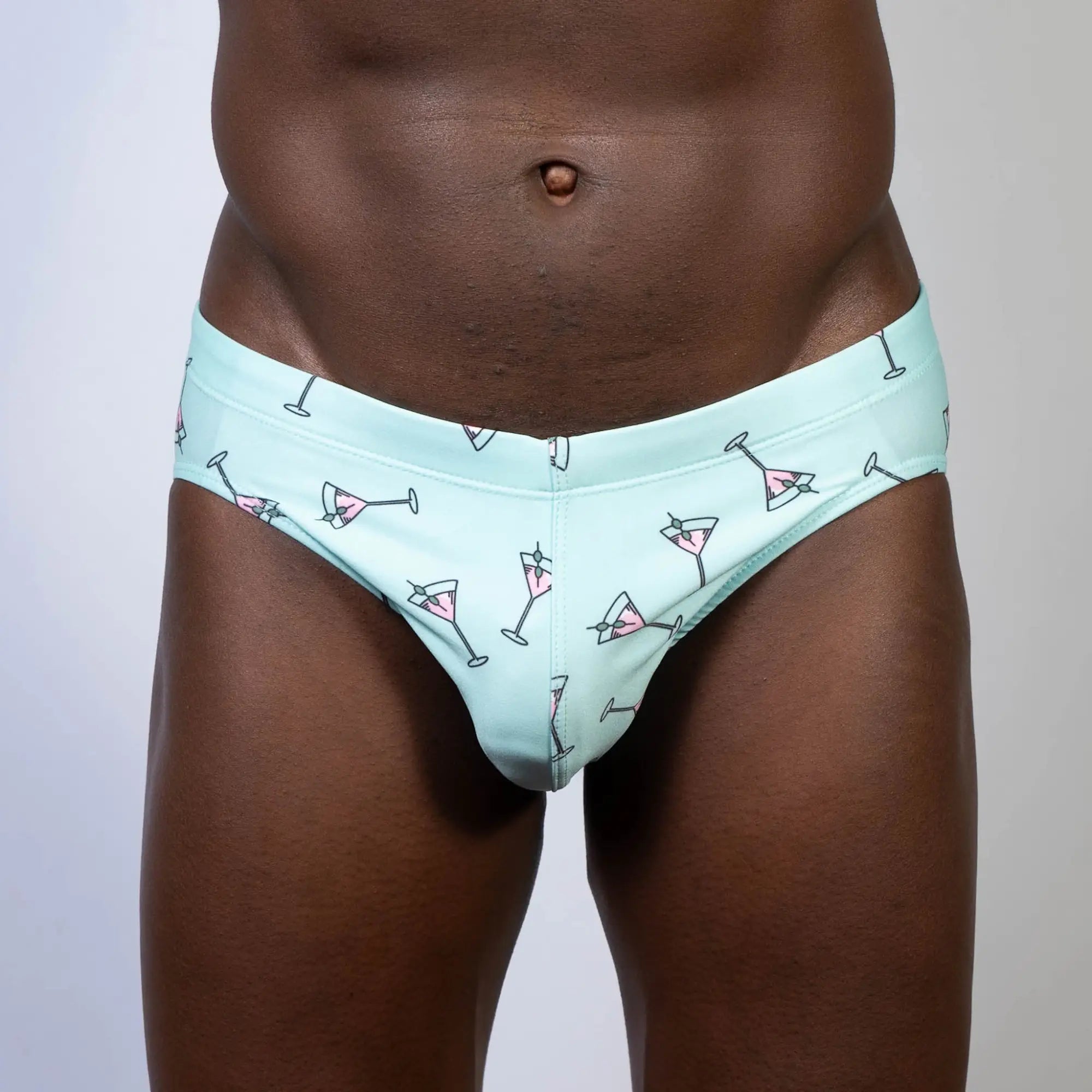 Mint green martini swim brief with playful pink martini glass pattern and black outlines for swimwear use