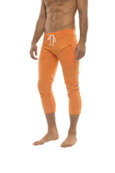 Mens solid orange capri yoga pants with bright orange swim trunk style, white drawstring waistband, and zipper pockets
