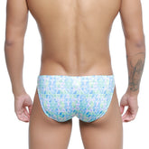 A man wearing metromalewear classic swim bikini glass 4937-62 men’s swim trunks with blue green and white geometric pattern