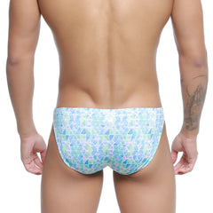 A man wearing metromalewear classic swim bikini glass 4937-62 men’s swim trunks with blue green and white geometric pattern