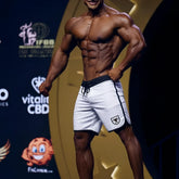 White athletic board shorts with black trim and shield logo on left leg from metromalewear avalanche physique line