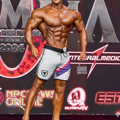 Gray metromusclewear ifbb pro mens physique board shorts with black trim purple pink stripe and white bull logo