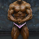 A muscular bodybuilder wearing black and purple MetroMaleWear MetroMuscleWear Mark competition briefs