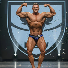 A muscular man flexing in a royal blue and black MetroMaleWear MetroMuscleWear Mark competition briefs number 23