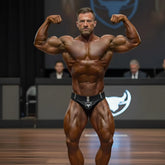 A muscular man flexing in black MetroMaleWear MetroMuscleWear Muscle Trunk Obsidiana 4700-42 briefs with white bull logo