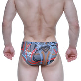 Gray swim trunks with bold red orange and blue chain pattern and decorative bows metroMalewear padu bikini 5103-M34