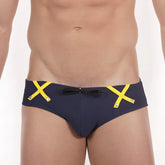 Navy blue MetroMaleWear Scottish swim brief with bold yellow x-shaped straps and black bow at the front