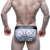 White men’s briefs with playful fried egg pattern black trim and metrcwear brand on waistband metro male wear sunny side bikini
