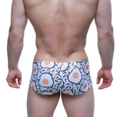 White swim trunks from metromalewear featuring a playful fried egg pattern with orange yolks and black outlines