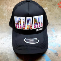 Black trucker hat featuring colorful embroidered miami design with palm trees and cityscape in vibrant hues