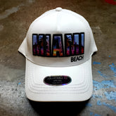 White baseball cap with vibrant colorful Miami Beach patch featuring urban skyline design and black trim
