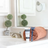 Blue and black five-blade disposable razor resting on a rolled terracotta towel with mixologie manscaping cream shave lotion sent iii