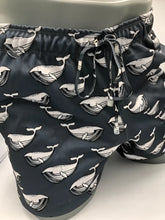 Black swim trunks featuring a repeating white whale pattern with detailed line art from moby dick shorts collection