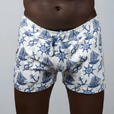 White linen texture swim trunks with blue nautical pattern of anchors sailboats and ship wheels