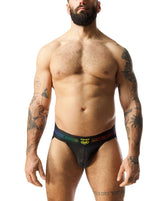 A muscular bearded man wearing the Nasty Pig Prism Pride black jockstrap with a rainbow waistband and logo.