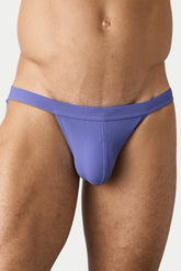 A man wearing lavender ribbed swim tanga briefs on a light background.