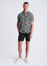 A man wearing a floral lightweight linen tencel short-sleeved shirt with a multicolored pattern on a dark background