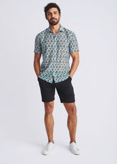 A man wearing a swirls lightweight cotton silk short sleeve shirt with blue teal and beige circular pattern