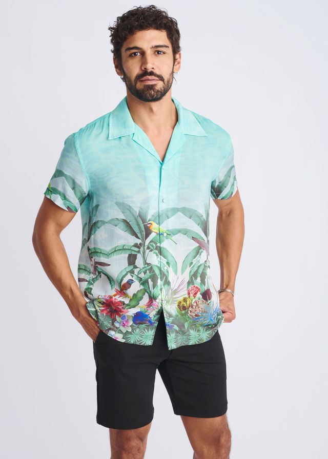 A men’s short-sleeved button-up modal shirt in vibrant turquoise with a tropical print of green leaves and colorful birds