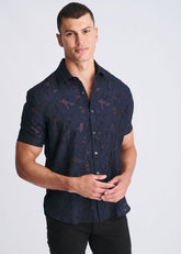 Man wearing a short-sleeve, navy blue jacquard shirt with a subtle floral pattern against a light background.