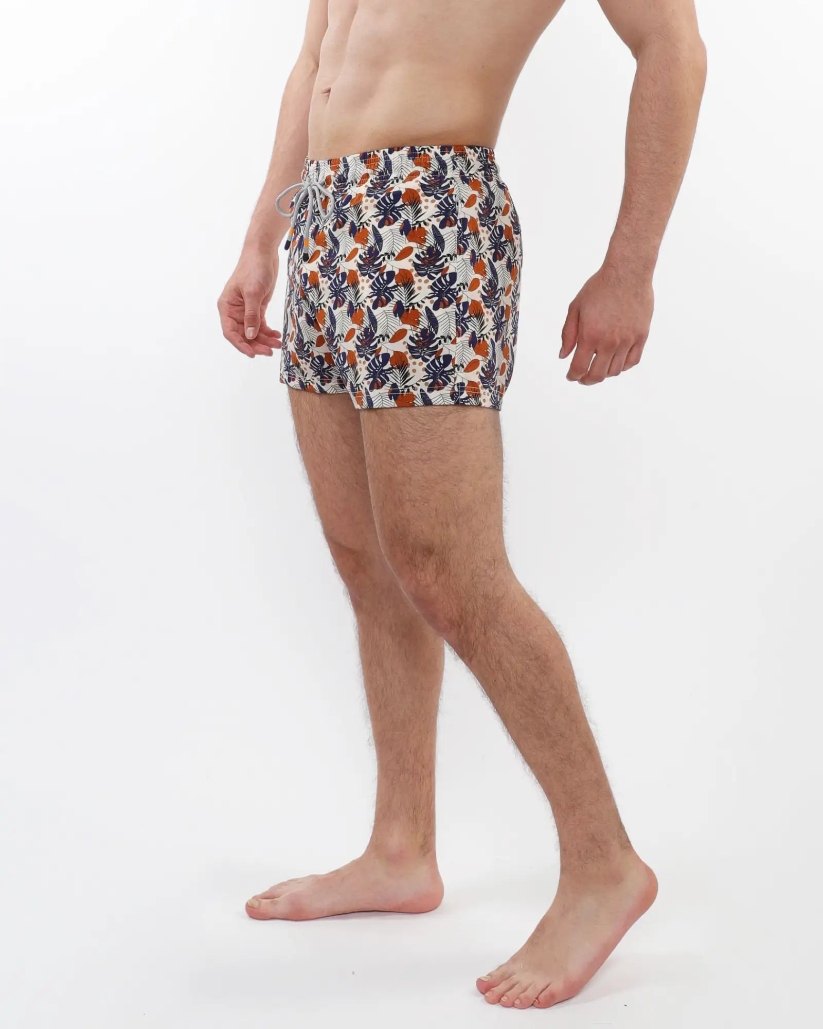 Printed swim short with mesh lining featuring vibrant tropical leaf and fruit pattern in navy orange and cream on white base