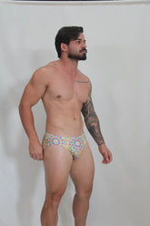 Rainbow Kaleidoscope swim brief featuring vibrant geometric pattern in blue yellow and red perfect for beachwear