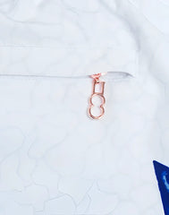 Rose gold-colored figure eight zipper pull attached to white fabric on s50 seascape print swim short