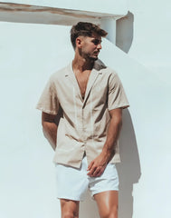 Beige santorini linen shirt with short sleeves and subtle white stitching along the placket and front seams