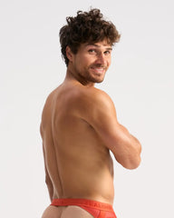 A man wearing bright red score sheer jock briefs with a visible Calvin Klein logo waistband from the front