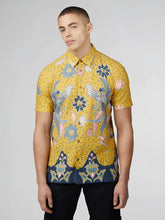 Yellow short-sleeved button-up shirt with intricate blue pink and white floral and bird patterns on dotted background