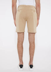 Beige solid stretch knit shorts with tailored fit and buttoned back pockets shown from the back side